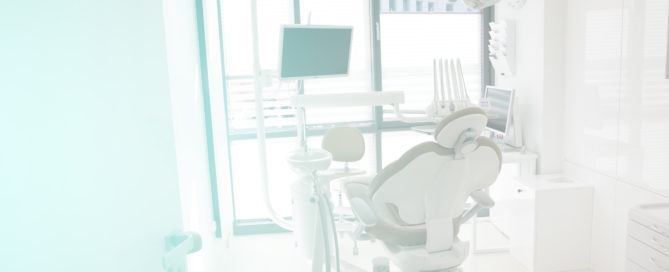 A dentist 's office with a chair and equipment.