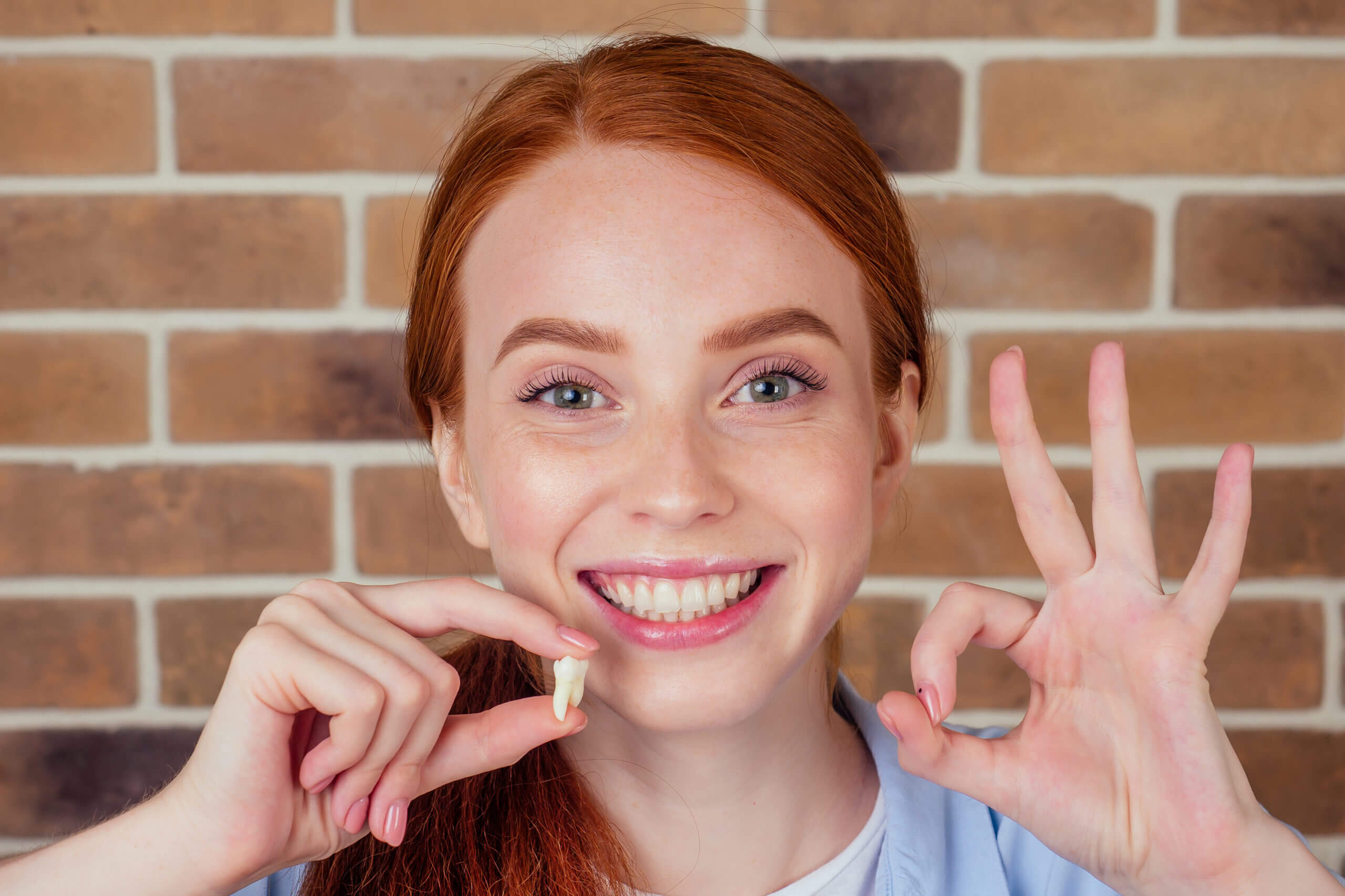 A woman holding up her fingers to show the tooth.