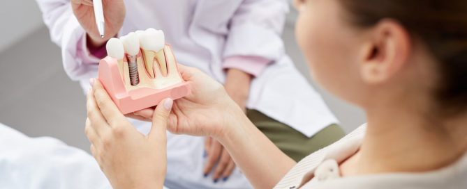 A woman is holding her teeth in front of the dentist.