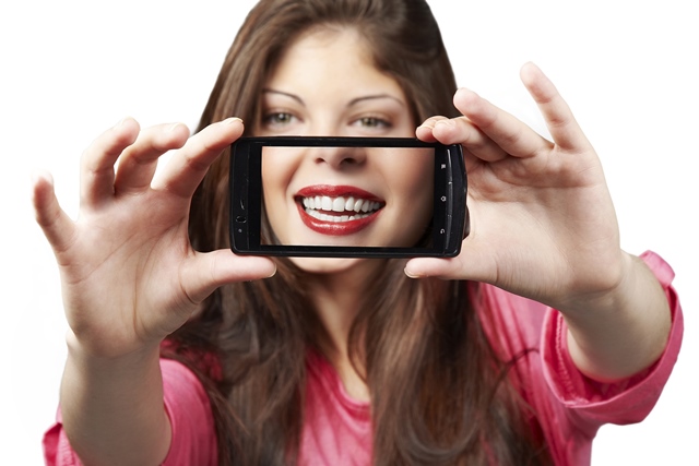 A woman taking a picture of herself with her phone.