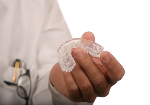 A person holding an orthodontic appliance in their hand.