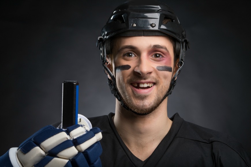 A man in black shirt holding a hockey stick.