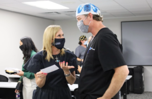 A woman and man wearing surgical masks talking to each other.