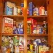A cupboard filled with lots of food and boxes.