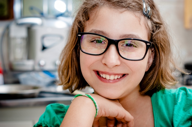 A girl with glasses smiling for the camera.