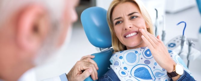 A woman sitting in the dentist chair with her teeth looking at the camera.