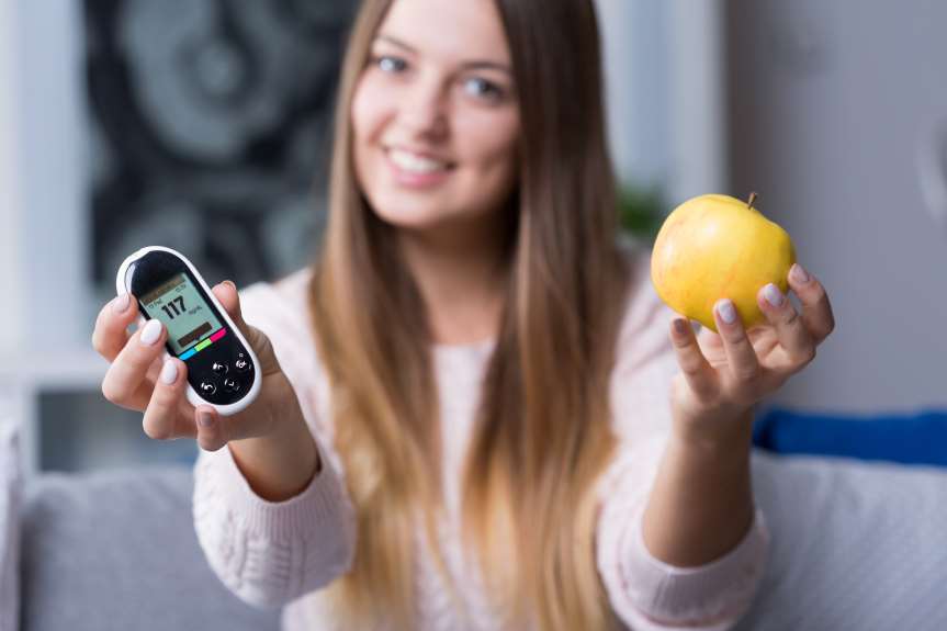 A woman holding an apple and a cell phone.