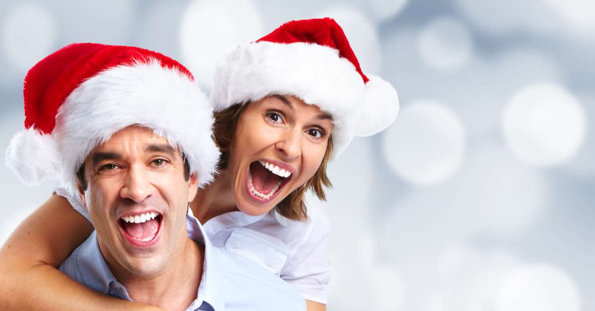 A man and woman wearing santa hats posing for the camera.