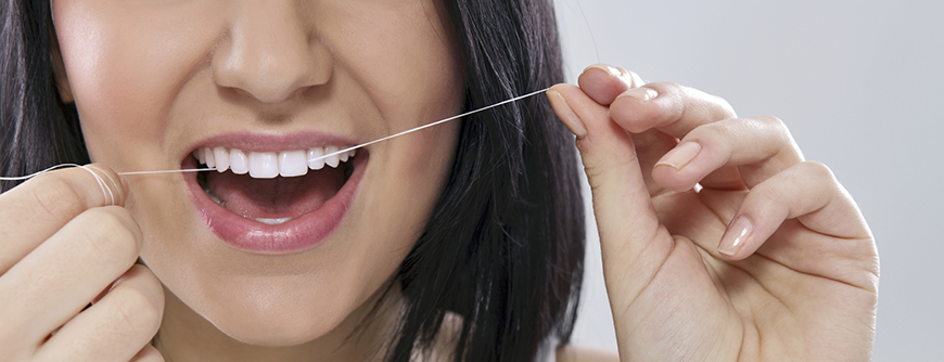 A woman is holding a tooth brush in her mouth.