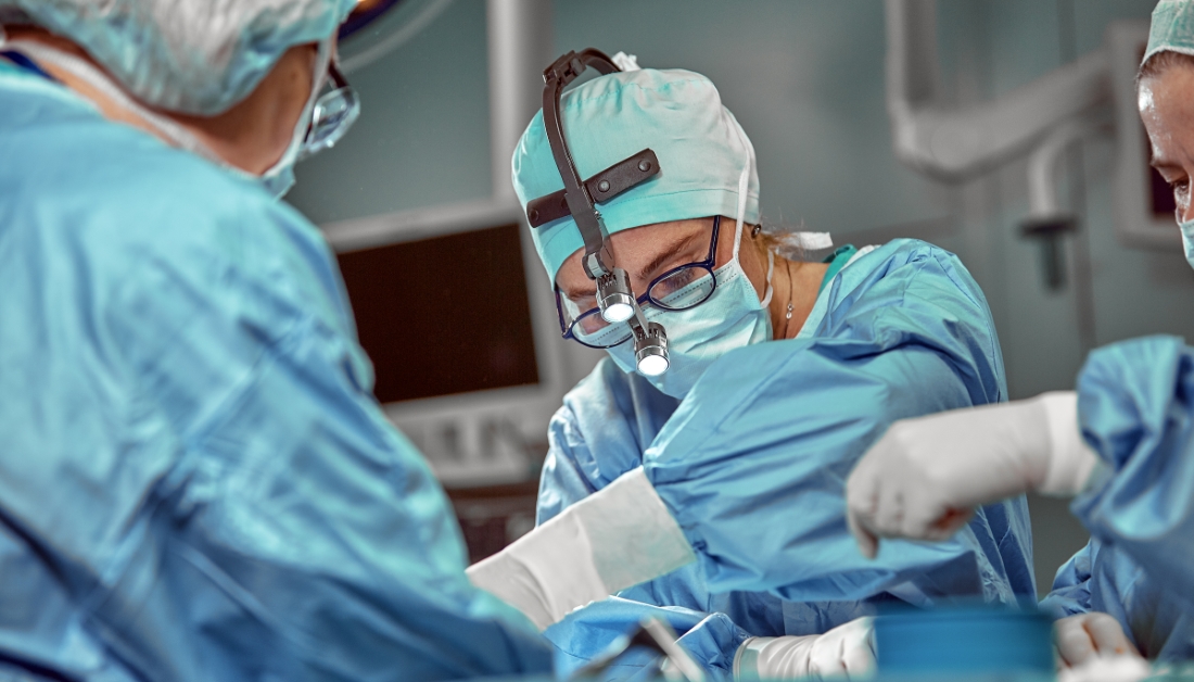 A surgeon is performing surgery on someone in the operating room.