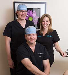 Three people in scrubs and hats are posing for a picture.