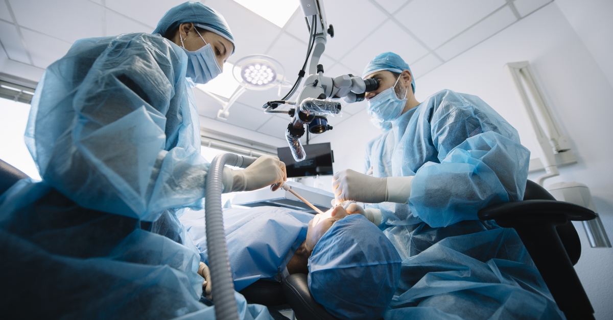A group of surgeons performing surgery on someone in the operating room.