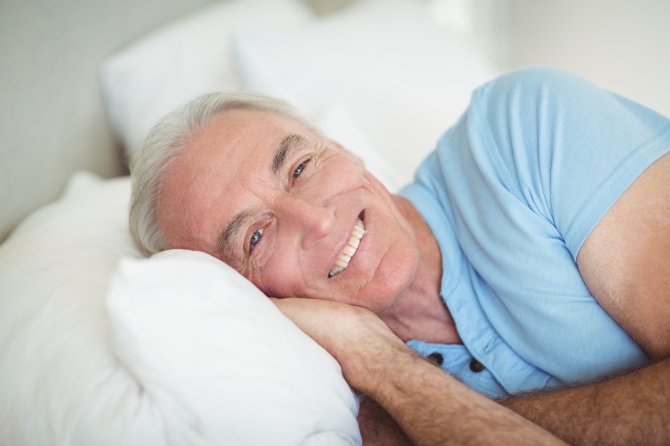 A man laying in bed smiling at the camera.