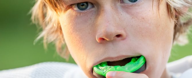 A boy with green teeth is brushing his teeth.