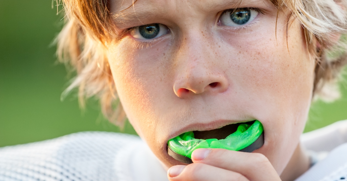 A boy with green teeth is brushing his teeth.
